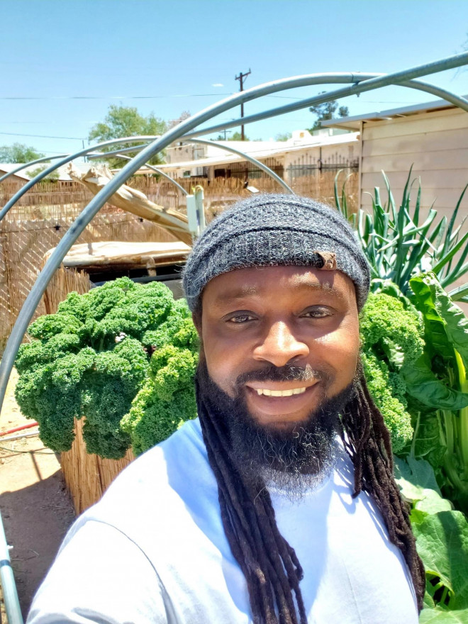 Charles Collins takes a selfie while standing in front of the aquaponics system in his garden.